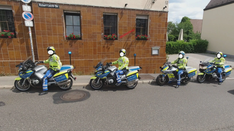 Vier Polizisten auf Motorrädern stehen am Fahrbahnrand und warten.